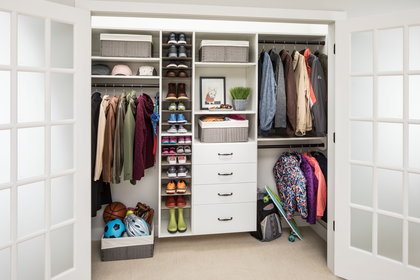 Reach-in closet behind French doors with central shoe shelving, drawers, and double-hang rods in a Delaware home
