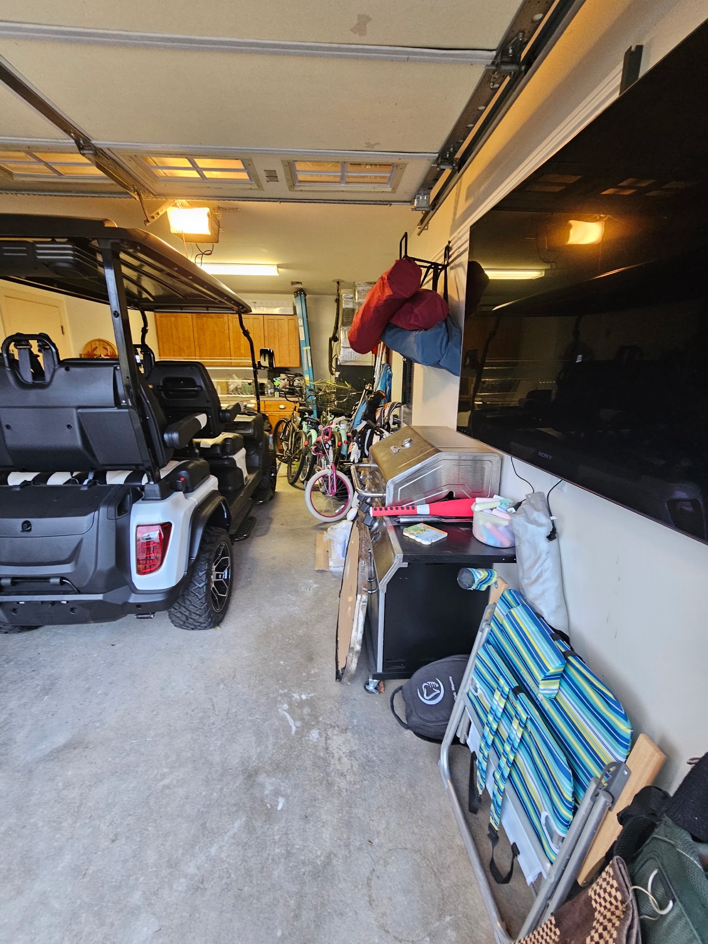 Bare, stained and dusty garage concrete with gear and a golf cart on it, before coating