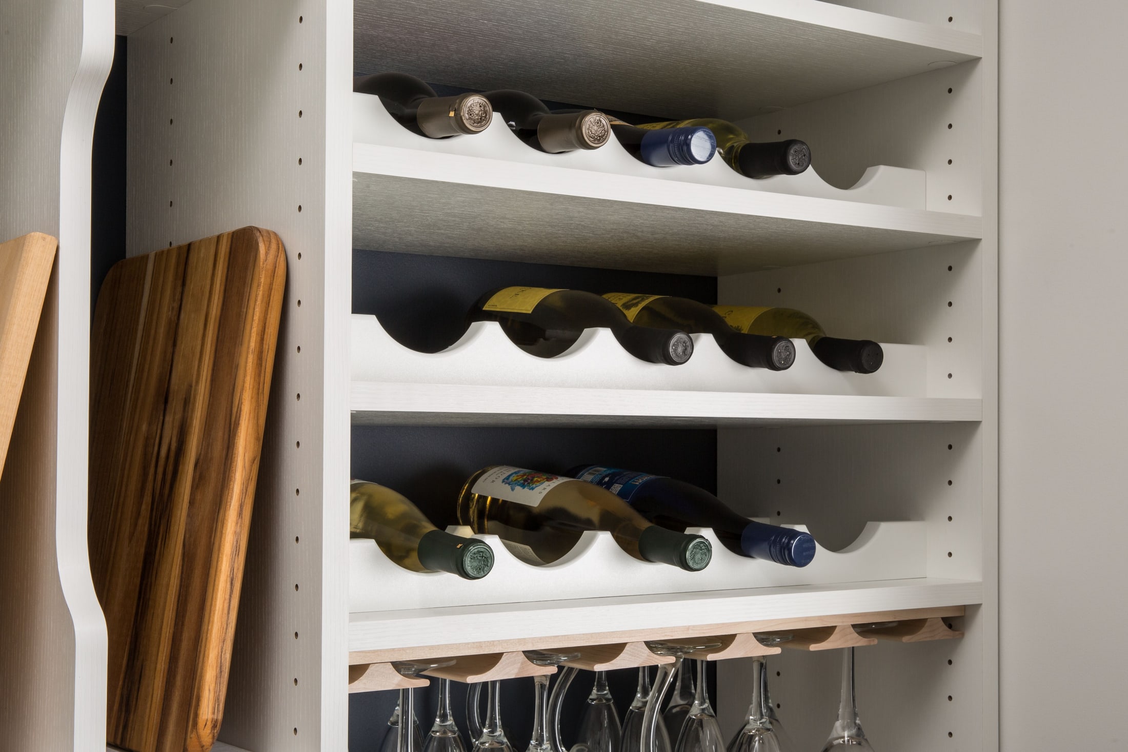 Built-in pantry wine rack holding bottles on three scalloped shelves above a stemware rail, by Atlantic Source in Delaware