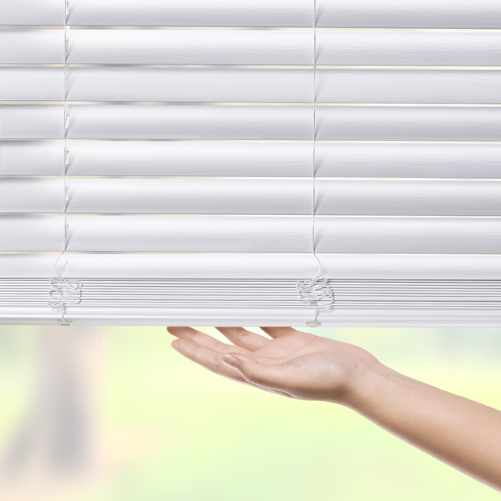 Hand tilting white Ashford faux wood blind slats to control light